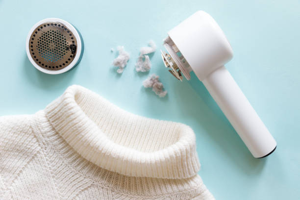 White handheld hair dryer and a white sweater on a light blue background